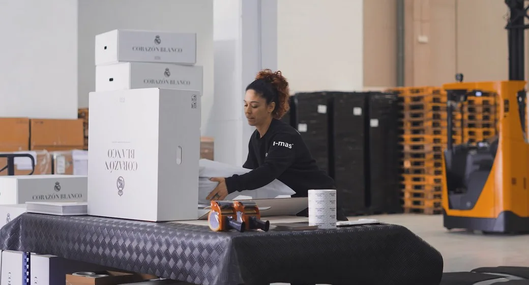 Worker at i-mas packaging finished product next to the dispatch trolley.