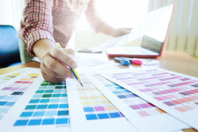 Woman working with color samples for selection. Graphic designer at work. Color swatch samples.